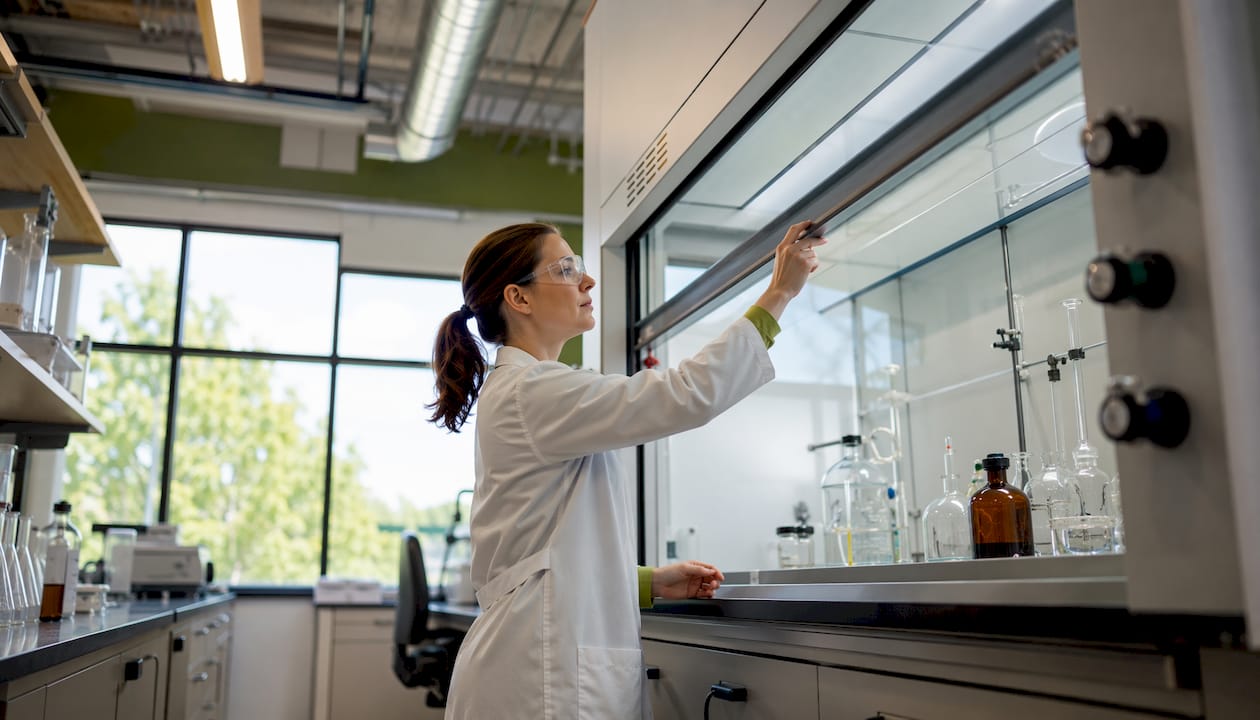 Researcher adjusting lab fume hood sash